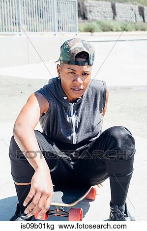 Woman sitting on skateboard looking at camera View Large Photo Image Stock Image - Woman sitting on skateboard looking at camera. Fotosearch