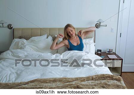 Woman sitting up and stretching arms in bed View Large Photo Image Stock Image - Woman sitting up and stretching arms in bed. Fotosearch