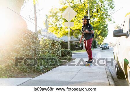 Woman skateboarding on pavement, looking at smartphone View Large Photo Image Stock Photography - Woman skateboarding on pavement, looking at smartphone. Fotosearch