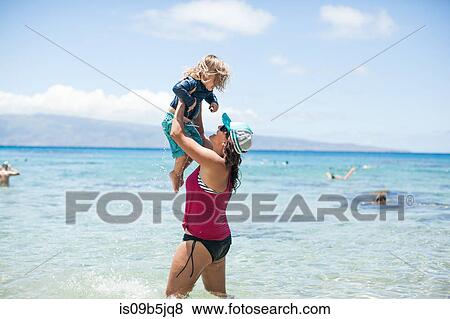 Woman standing in sea, lifting son in air View Large Photo Image Stock Photo - Woman standing in sea, lifting son in air. Fotosearch