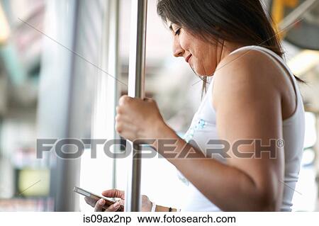 Woman standing on bus reading smartphone texts, Los Angeles, California, USA View Large Photo Image Stock Photography - Woman standing on bus reading smartphone texts, Los Angeles, California, USA. Fotosearch