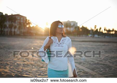 Stock Photo - Woman strolling on Santa Monica beach at sunset, Cresent City, California, USA. Fotosearch