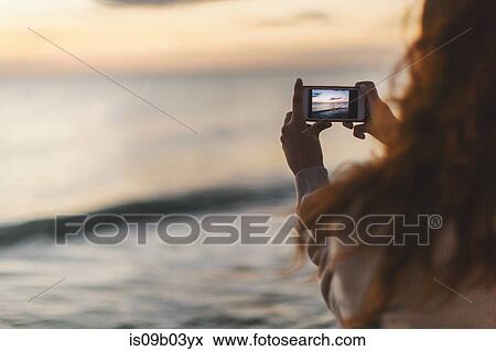 Woman taking photograph with mobile phone on beach View Large Photo Image Stock Photo - Woman taking photograph with mobile phone on beach. Fotosearch