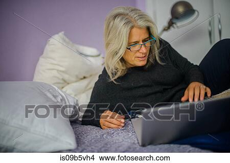 Woman using laptop in bed View Large Photo Image Picture - Woman using laptop in bed. Fotosearch