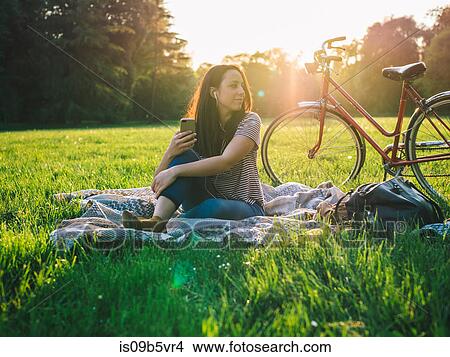 Woman using mobile phone on grass View Large Photo Image Picture - Woman using mobile phone on grass. Fotosearch