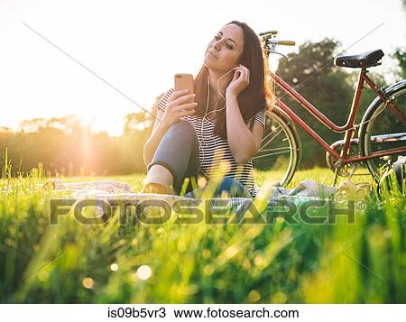 Stock Image - Woman using mobile phone on grass. Fotosearch