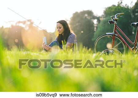 Woman using mobile phone on grass View Large Photo Image Stock Photo - Woman using mobile phone on grass. Fotosearch