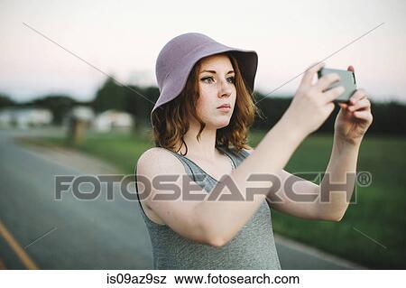Stock Photo - Woman using smartphone to take photograph. Fotosearch