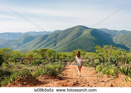 Stock Photo - Woman walking along dirt pathway, rear view, Hierve el Agua, Oaxaca, Mexico.. Fotosearch
