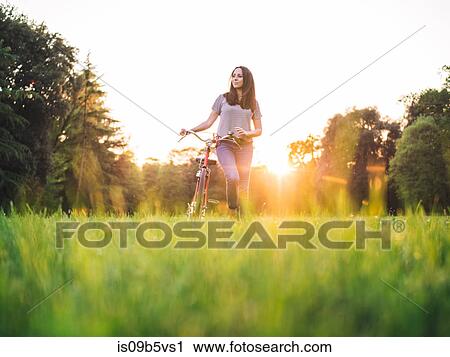 Woman walking bicycle on grass View Large Photo Image Stock Image - Woman walking bicycle on grass. Fotosearch
