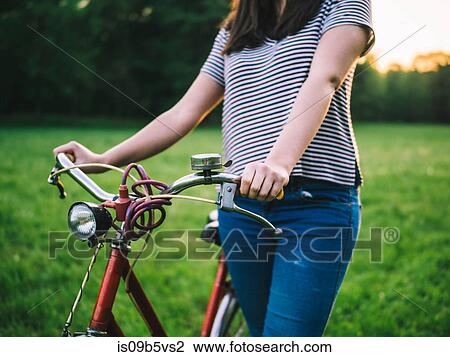 Woman walking bicycle on grass View Large Photo Image Stock Image - Woman walking bicycle on grass. Fotosearch
