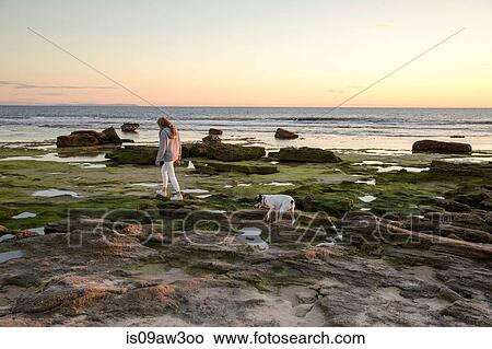 Picture - Woman walking dog along rocky beach, Cape of Trafalgar, Spain. Fotosearch
