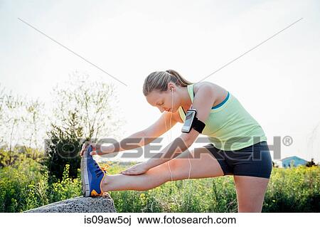 Woman wearing activity tracker bending forward touching toes stretching View Large Photo Image Stock Image - Woman wearing activity tracker bending forward touching toes stretching. Fotosearch