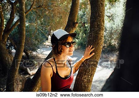 Woman wearing baseball cap and sunglasses sitting in tree View Large Photo Image Stock Image - Woman wearing baseball cap and sunglasses sitting in tree. Fotosearch