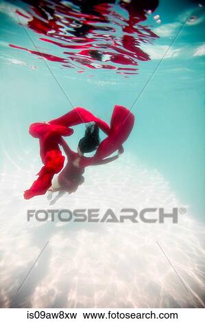Woman wearing red dress, draped in red fabric, floating underwater View Large Photo Image Stock Photo - Woman wearing red dress, draped in red fabric, floating underwater. Fotosearch