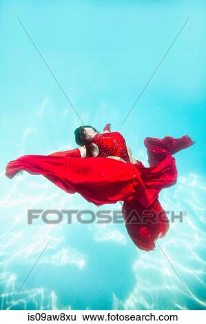 Woman wearing red dress, draped in red fabric, floating underwater View Large Photo Image Stock Photograph - Woman wearing red dress, draped in red fabric, floating underwater. Fotosearch