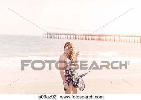Stock Image - Woman wearing sarong on beach looking at camera, Coney island, Brooklyn, New York, USA. Fotosearch
