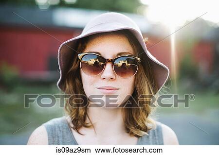 Woman wearing sunglasses and sun hat looking at camera View Large Photo Image Picture - Woman wearing sunglasses and sun hat looking at camera. Fotosearch