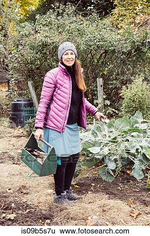 Woman working in garden holding box of garden tools View Large Photo Image Stock Photograph - Woman working in garden holding box of garden tools. Fotosearch