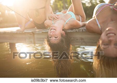 Stock Photo - Women lying back on pier dangling long wet hair, Santa Rosa Beach, Florida, USA. Fotosearch
