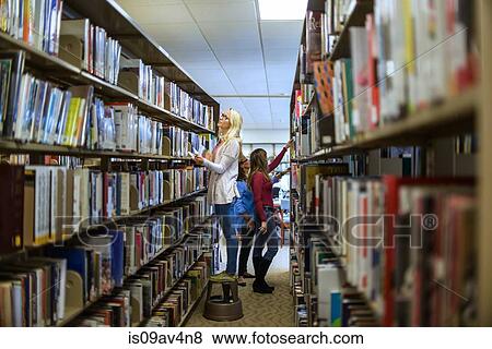 Stock Photo - Women searching for books in library. Fotosearch