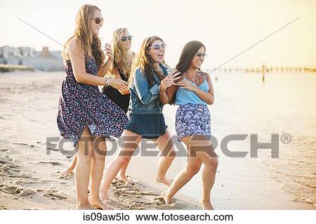 Women wearing sunglasses on beach fooling around laughing View Large Photo Image Picture - Women wearing sunglasses on beach fooling around laughing. Fotosearch
