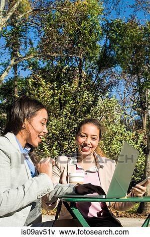 Young adult female twins typing on laptop in city park View Large Photo Image Stock Photo - Young adult female twins typing on laptop in city park. Fotosearch