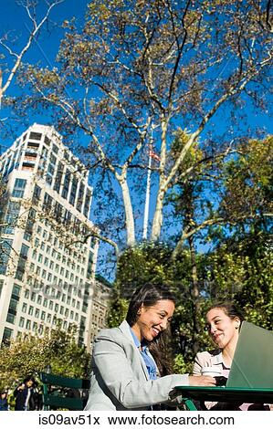 Young adult female twins using laptop in city park View Large Photo Image Stock Photo - Young adult female twins using laptop in city park. Fotosearch