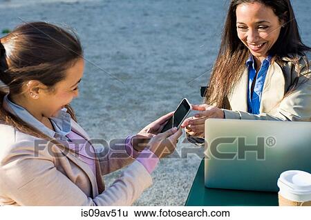 Young adult female twins using laptop and smartphone at sidewalk cafe View Large Photo Image Stock Photograph - Young adult female twins using laptop and smartphone at sidewalk cafe. Fotosearch