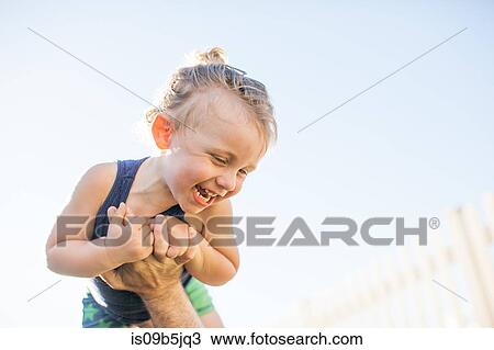 Stock Image - Young boy being lifted in air by father. Fotosearch