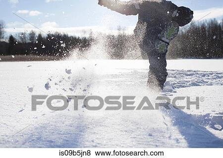 Young boy kicking snow, in snow covered landscape, low section View Large Photo Image Stock Photo - Young boy kicking snow, in snow covered landscape, low section. Fotosearch