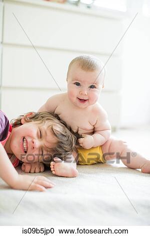 Stock Image - Young boy playing with baby sister, indoors. Fotosearch