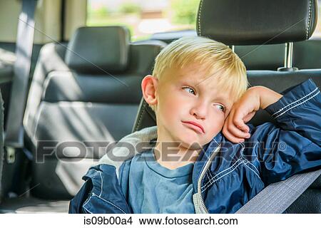 Young boy sitting in back of vehicle, bored expression View Large Photo Image Picture - Young boy sitting in back of vehicle, bored expression. Fotosearch