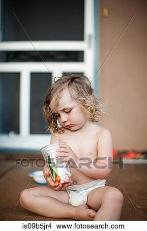 Young boy sitting on porch, holding plastic cup with fresh fruit and vegetables View Large Photo Image Picture - Young boy sitting on porch, holding plastic cup with fresh fruit and vegetables. Fotosearch