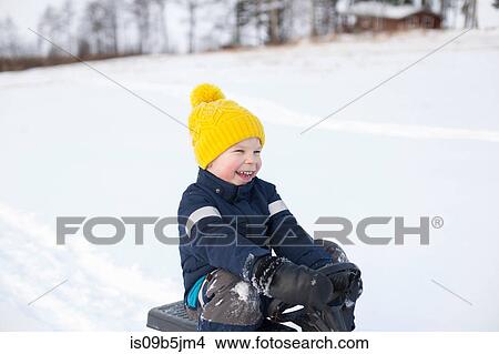 Young boy sitting on sledge, in snow covered landscape View Large Photo Image Picture - Young boy sitting on sledge, in snow covered landscape. Fotosearch