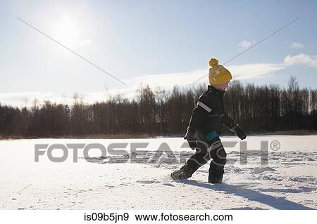 Young boy walking in snow covered landscape View Large Photo Image Stock Photo - Young boy walking in snow covered landscape. Fotosearch