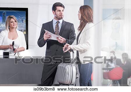 Young businessman and woman with paperwork at hotel reception desk View Large Photo Image Stock Photo - Young businessman and woman with paperwork at hotel reception desk. Fotosearch