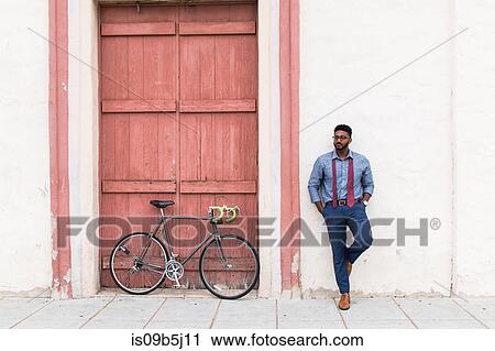 Young businessman cyclist leaning against wall waiting View Large Photo Image Stock Image - Young businessman cyclist leaning against wall waiting. Fotosearch