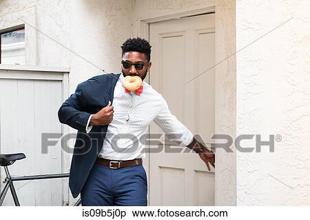 Young businessman eating doughnut and closing front door View Large Photo Image Stock Photography - Young businessman eating doughnut and closing front door. Fotosearch