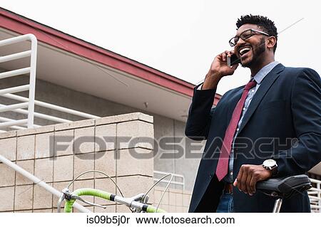 Stock Photography - Young businessman making smartphone call on railway station platform. Fotosearch
