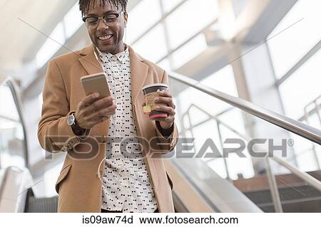 Young businessman moving down train station escalator reading smartphone View Large Photo Image Stock Image - Young businessman moving down train station escalator reading smartphone. Fotosearch