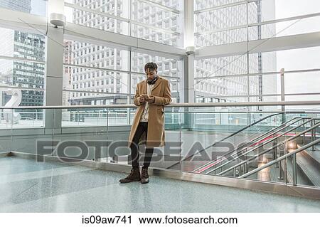 Young businessman selecting smartphone music in train station atrium View Large Photo Image Stock Image - Young businessman selecting smartphone music in train station atrium. Fotosearch