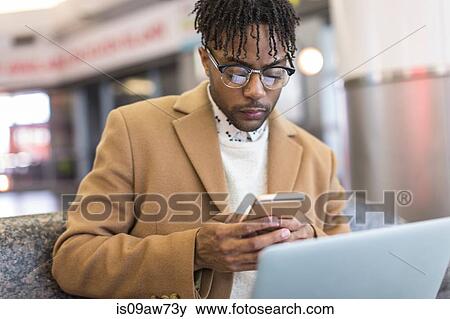 Young businessman sitting in train station texting on smartphone View Large Photo Image Stock Photo - Young businessman sitting in train station texting on smartphone. Fotosearch