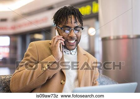 Young businessman sitting in train station talking on smartphone View Large Photo Image Stock Photo - Young businessman sitting in train station talking on smartphone. Fotosearch