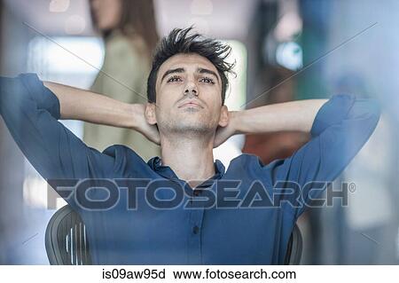 Young businessman sitting with hands behind neck View Large Photo Image Stock Image - Young businessman sitting with hands behind neck. Fotosearch