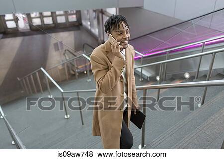 Young businessman talking on smartphone moving up train station stairway View Large Photo Image Stock Photo - Young businessman talking on smartphone moving up train station stairway. Fotosearch