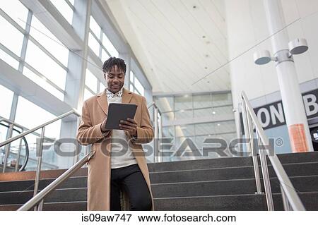 Young businessman using digital tablet moving down train station stairway View Large Photo Image Stock Photo - Young businessman using digital tablet moving down train station stairway. Fotosearch