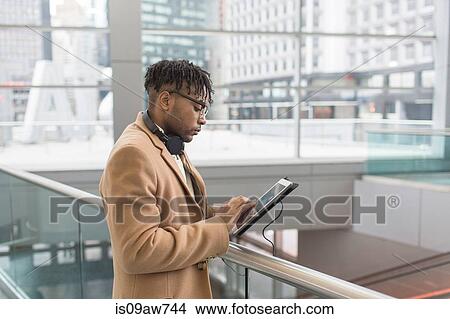 Young businessman using touchscreen on digital tablet in train station atrium View Large Photo Image Picture - Young businessman using touchscreen on digital tablet in train station atrium. Fotosearch