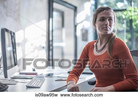 Young businesswoman sitting at desk View Large Photo Image Stock Photo - Young businesswoman sitting at desk. Fotosearch
