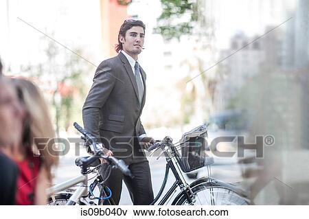 Young confident businessman pushing bicycle in city View Large Photo Image Stock Photo - Young confident businessman pushing bicycle in city. Fotosearch